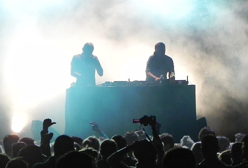 Philippe Zdar et BoomBass de Cassius derrière leurs machines, éclairés depuis l’arrière devant le public du Festival RockAdel.