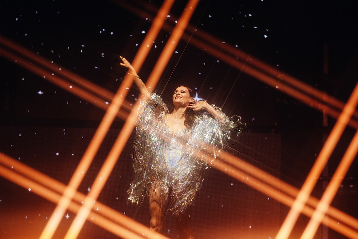 Sophie Ellis-Bextor en tenue miroir au centre de faisceaux lumineux orange